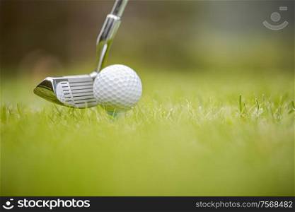 Golf club and ball on tee in front of driver