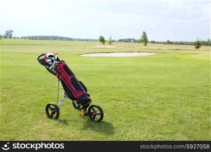 Golf club bag on pushcart at golf course against sky