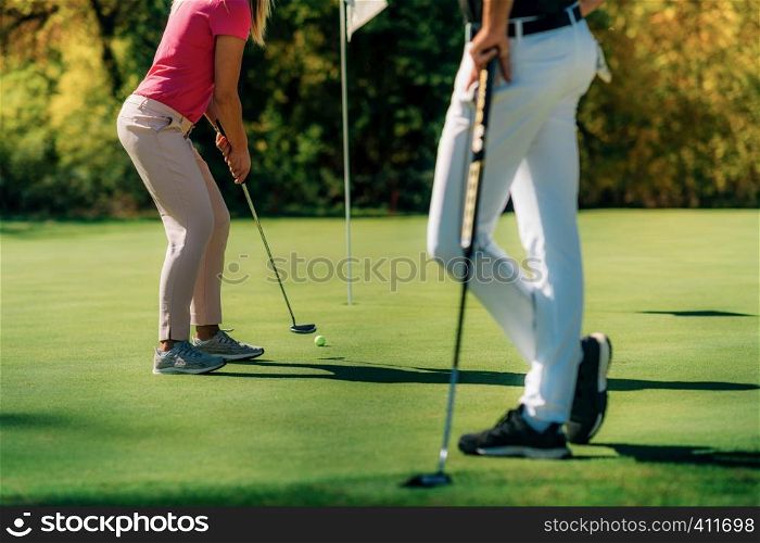 Golf couple putting on the green, unrecognizable people