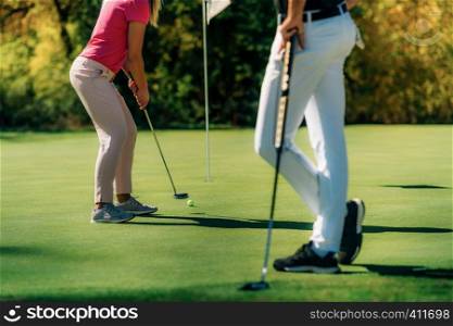 Golf couple putting on the green, unrecognizable people