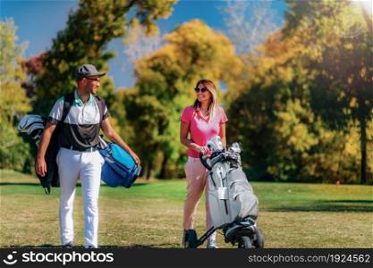 Golf couple walking to the next hole on a beautiful autumn day