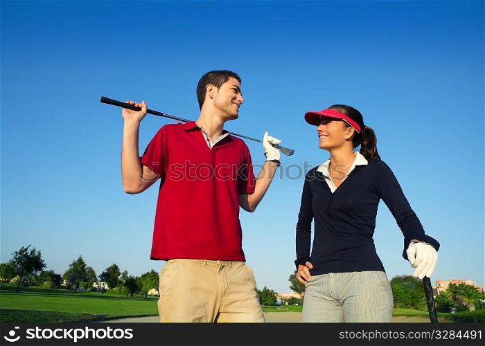 Golf course young happy players couple talking posing on bunker