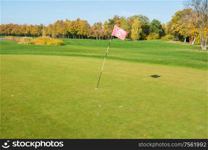 Golf flag near trap on green golf field