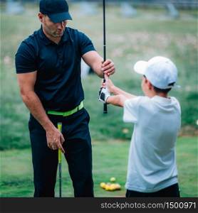 Golf Instructor adjusting young boy&rsquo;s grip