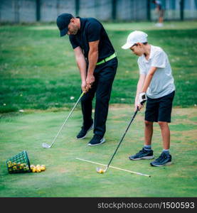 Golf Lessons. A golf Instructor and a boy practicing on a Golf Practice Range