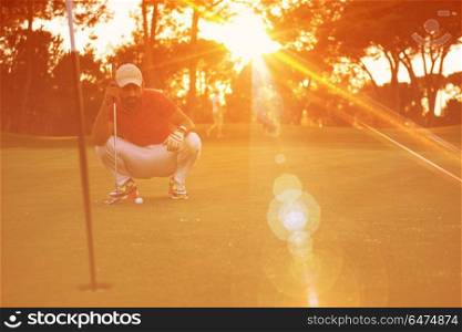 golf player aiming shot with club on course at beautiful sunset with sun flare in background. golf player aiming perfect shot on beautiful sunset