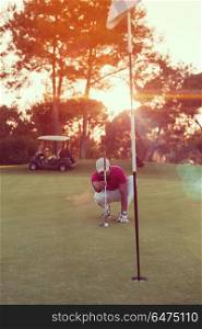 golf player aiming shot with club on course at beautiful sunset with sun flare in background. golf player aiming perfect shot on beautiful sunset