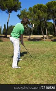 Golf player chipping his ball on the green of a luxurious golf course