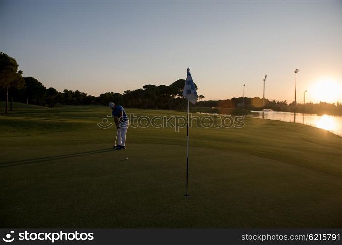 golf player hitting ball with driver on course at beautiful sunset