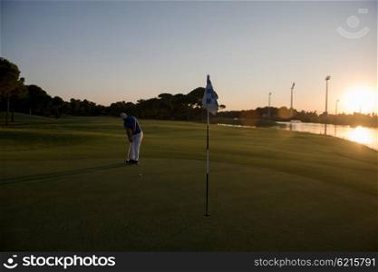 golf player hitting ball with driver on course at beautiful sunset