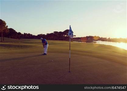 golf player hitting ball with driver on course at beautiful sunset. golfer hitting ball to hole