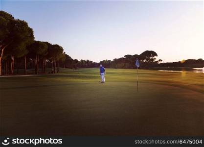 golf player hitting ball with driver on course at beautiful sunset. golfer hitting ball to hole