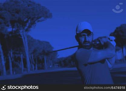 golf player hitting shot. golf player hitting shot with club on course at beautiful morning with sun flare in background duo tone