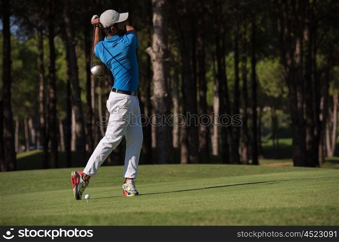 golf player hitting shot with club on course at beautiful morning
