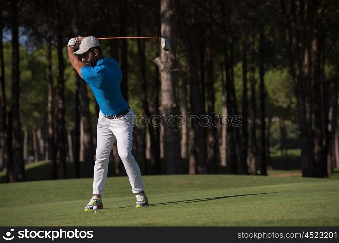 golf player hitting shot with club on course at beautiful morning
