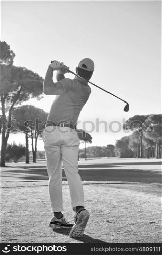 golf player hitting shot with club on course at beautiful morning black and white