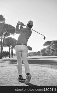 golf player hitting shot with club on course at beautiful morning black and white