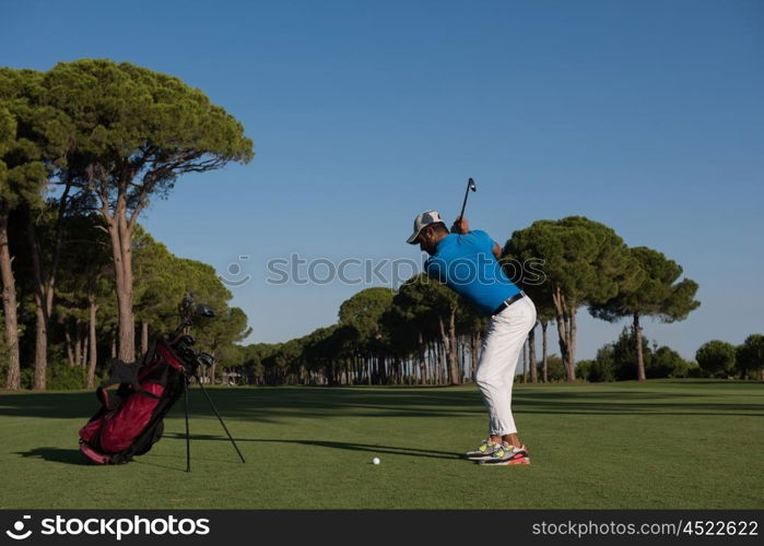 golf player hitting shot with club on course at beautiful morning with sun flare in background