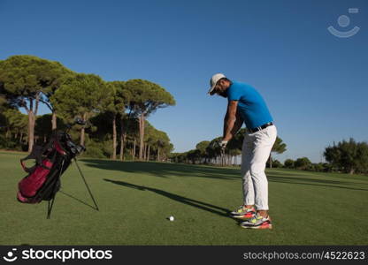 golf player hitting shot with club on course at beautiful morning with sun flare in background