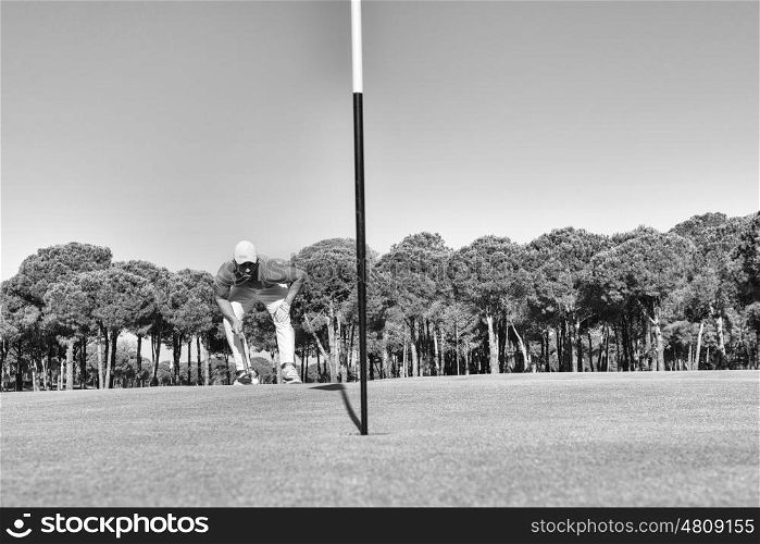 golf player hitting shot with club on course at beautiful morning with sun flare in background black and white