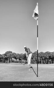 golf player hitting shot with club on course at beautiful morning with sun flare in background black and white