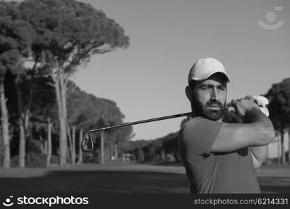 golf player hitting shot with club on course at beautiful morning with sun flare in background