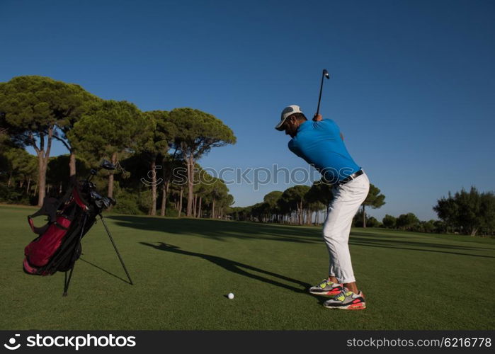 golf player hitting shot with club on course at beautiful morning with sun flare in background