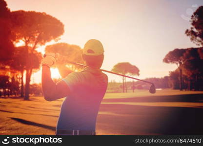 golf player hitting shot with club on course at beautiful morning with sun flare in background. golf player hitting shot with club