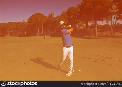golf player hitting shot with club on course at beautiful morning with sun flare in background. golf player hitting shot