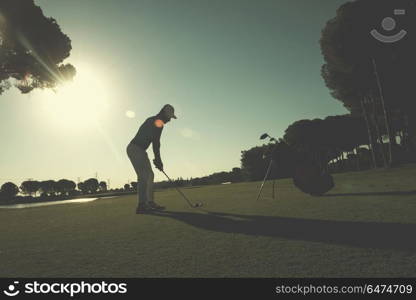 golf player hitting shot with club on course at beautiful morning with sun flare in background. golf player hitting shot