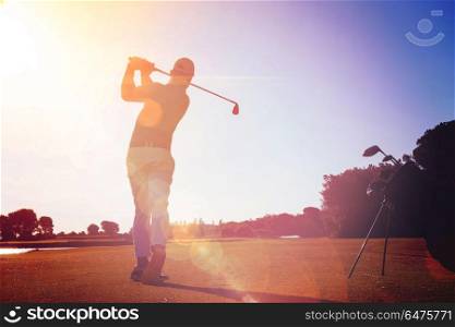 golf player hitting shot with club on course at beautiful morning with sun flare in background. golf player hitting shot with club