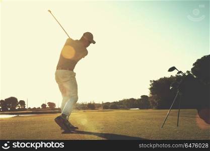 golf player hitting shot with club on course at beautiful morning with sun flare in background. golf player hitting shot with club