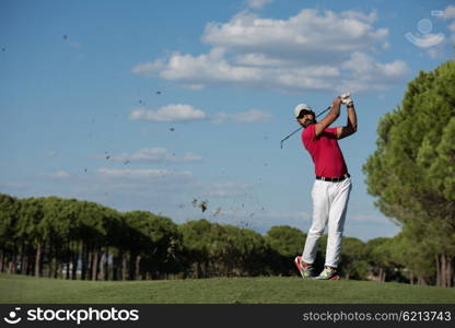 golf player hitting shot with driver on course at beautiful sunny day