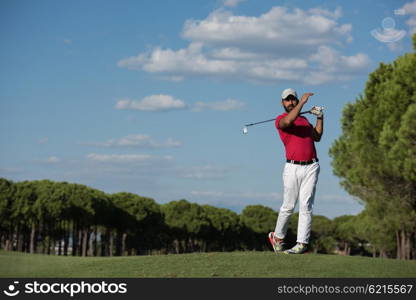 golf player hitting shot with driver on course at beautiful sunny day