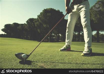 golf player placing ball on tee. beautiful sunrise on golf course landscape in background. golf player placing ball on tee