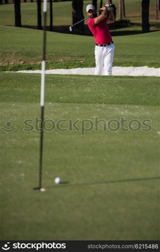 golf player shot ball from sand bunker at course