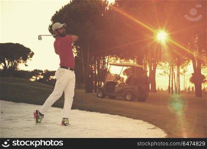 golf player shot ball from sand bunker at course with beautiful sunset with sun flare. golfer hitting a sand bunker shot on sunset