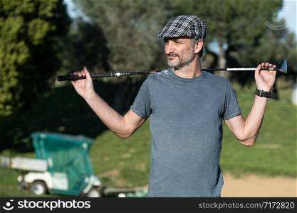 golf player with a cap holding a golf club on his back