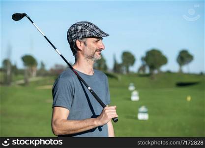 golf player with cap and club over his shoulder on a driving course