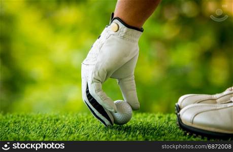 golf players hand placing ball on grass