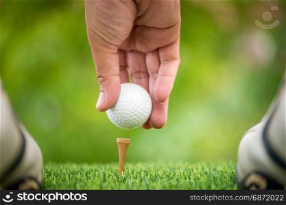 golf players hand placing ball on tee