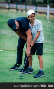 Golf Putting Training. Golf Instructor with Young Boy Practicing on the Putting Green