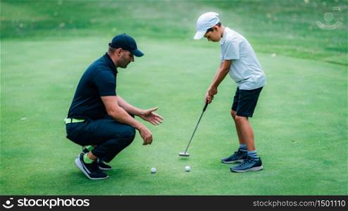 Golf Putting Training. Golf Instructor with Young Boy Practicing on the Putting Green