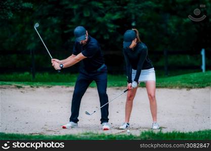 Golf sand bunker playing technique. Young woman practicing bunker shots with golf instructor