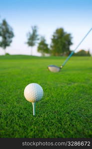 Golf tee ball club driver in green grass course horizon trees