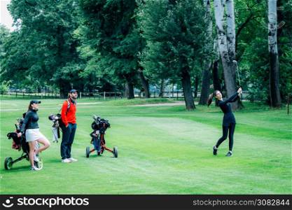 Golf training. Two young ladies with golf instructor having a lesson on a golf course