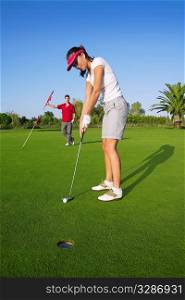 golf woman player green putting hole golf ball a man holding flag