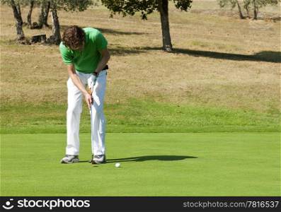 Golfer concentrating for a put on the green of a colf course