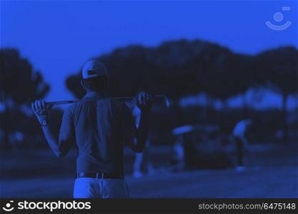 golfer from back at course looking to hole in distance. golfer from back looking to ball and hole in distance, handsome middle eastern golf player portrait from back with beautiful sunset in background duo tone