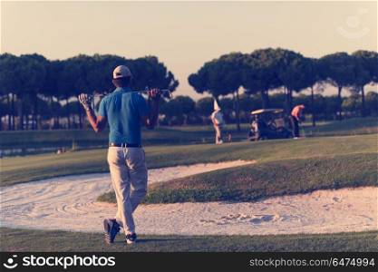 golfer from back looking to ball and hole in distance, handsome middle eastern golf player portrait from back with beautiful sunset in background. golfer from back at course looking to hole in distance